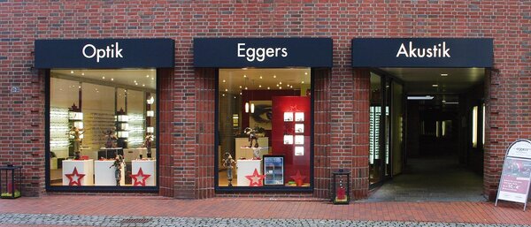 Fassade eines Optik- und Akustikgeschäfts mit Schaufenstern und moderner Beleuchtung.